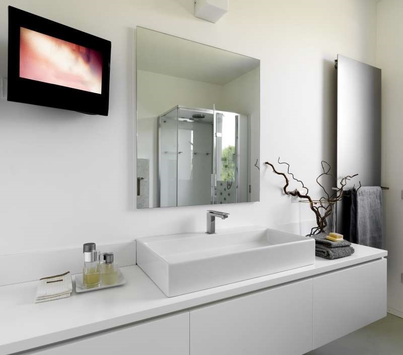 Lifestyle image of a television mounted on a bathroom wall next to a mirror cabinet