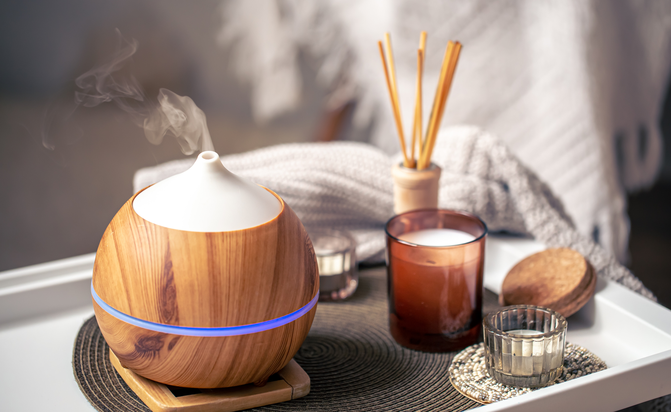 Lifestyle image of an electric oil diffuser on a tray next to various scented candles