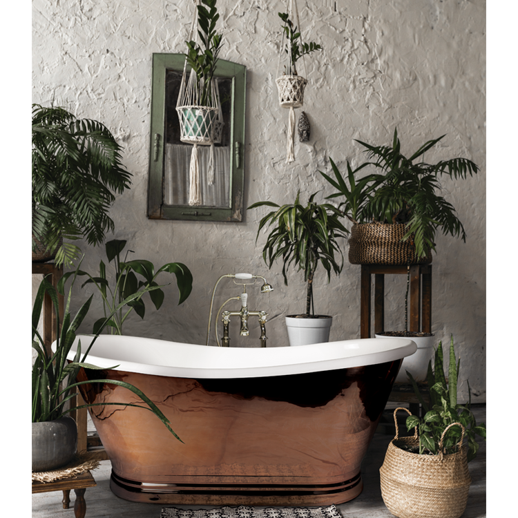 Prodcut Lifestyle image of the BC Designs 1500mm Copper & Enamel Freestanding Boat Bath surrounded by houseplants in vases and wicker baskets
