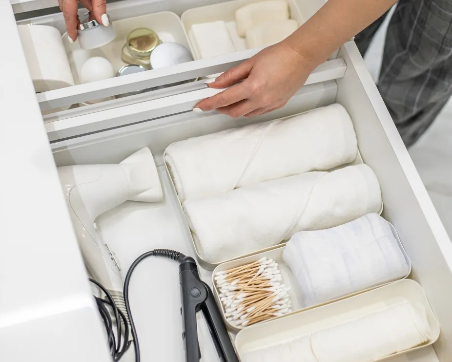image of an open drawer of a vanity unit with hair appliances, towels and make up items