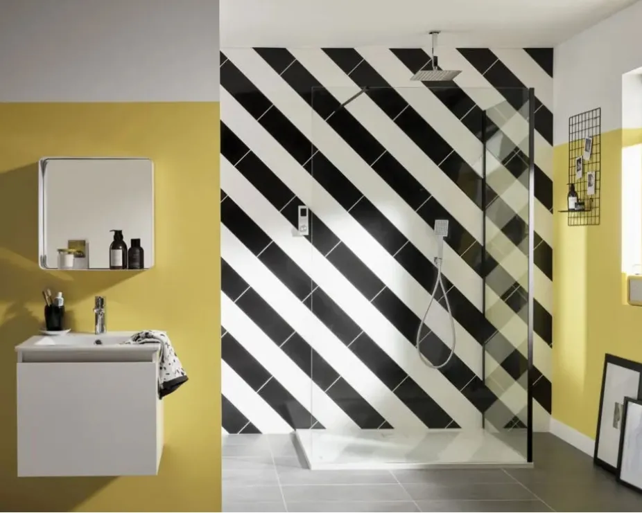 image of a large walk in shower space with ceiling mounted head, handshower and black and white tiled background