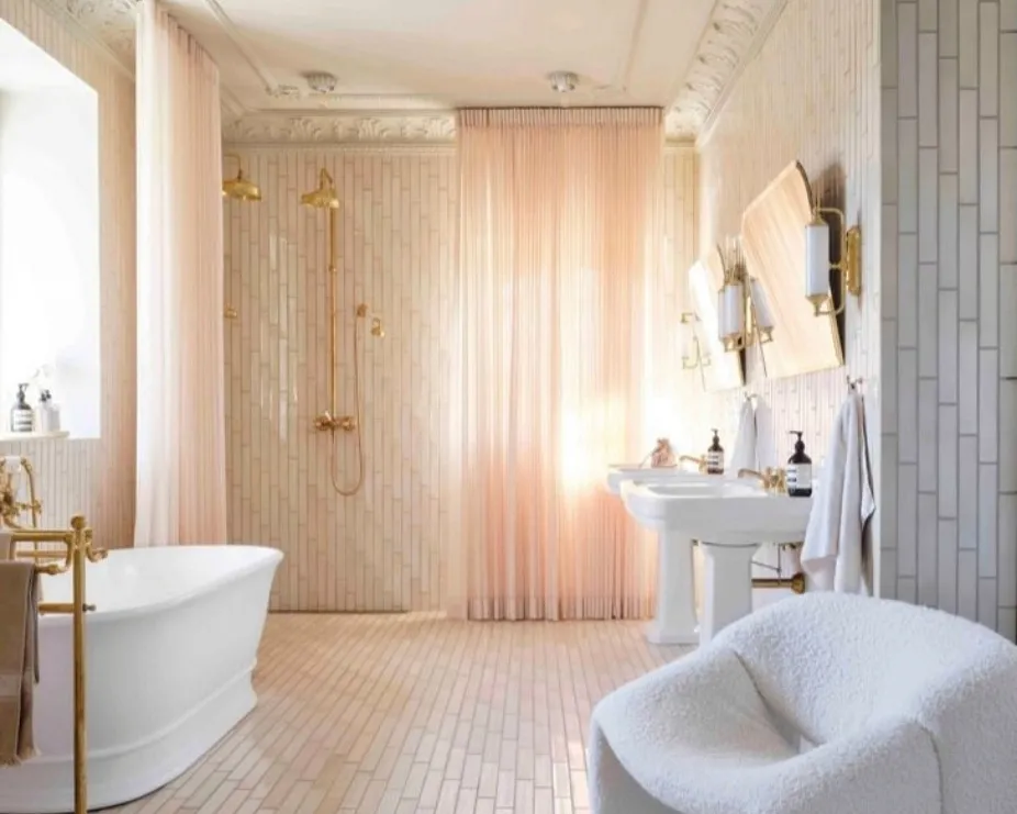 image of a bathroom with luxury freestanding bath, pedestal basins, mirrors and two showers in gold illustrating quiet luxury trend