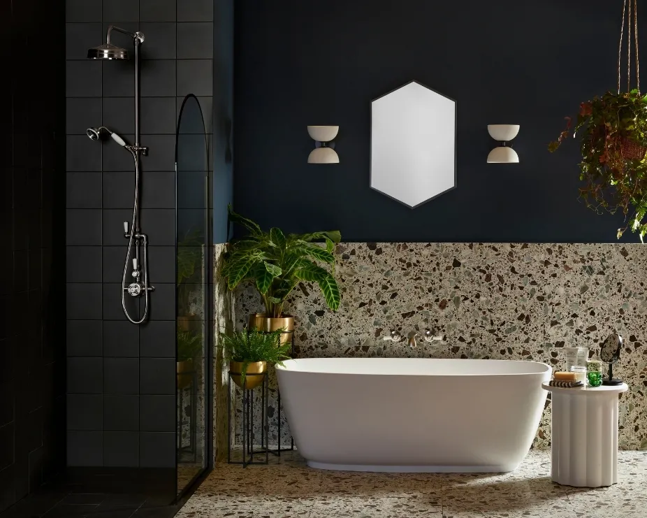 image of a freestanding bath in a dark, atmospheric bathroom with terrazzo wall and floor tiles underneath