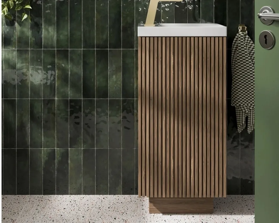 image of a darker wood cloakroom vanity unit with vertical grooves against a green brick tiled wall and terrazzo floor
