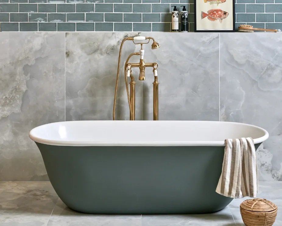 image of a grey painted freestanding bath in a grey marble tiled bathroom with gold freestanding tap