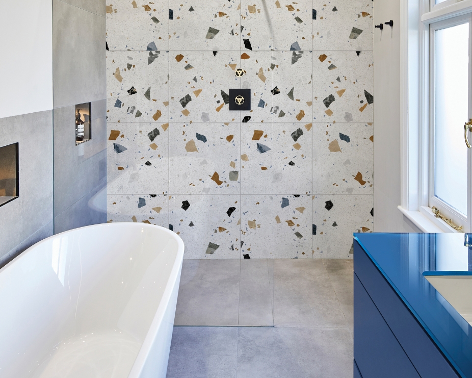 image of a terrazzo bathroom using ca pieta geo pearl tiles with a bath and blue vanity unit