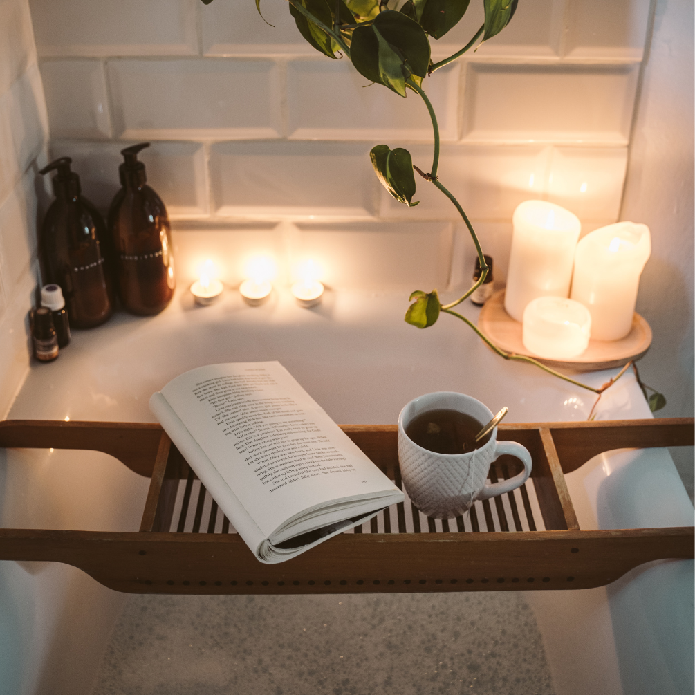 image of a relaxing bath with candeles and bath rack with book and drink