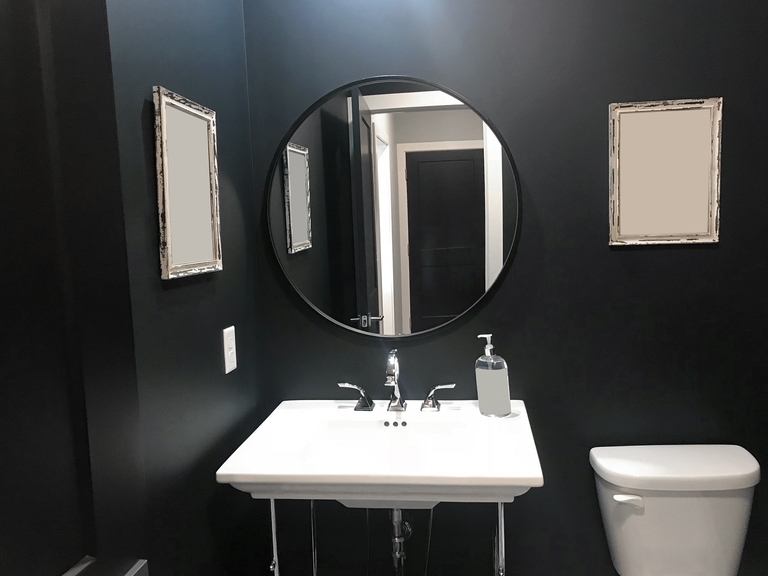 Lifestyle image of a black and white bathroom, with black wall and white ceramics