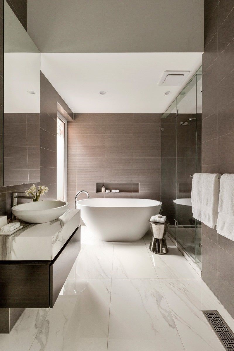 Lifestyle image of a marble tiled bathroom with a grey-brown wooden washbasin unit