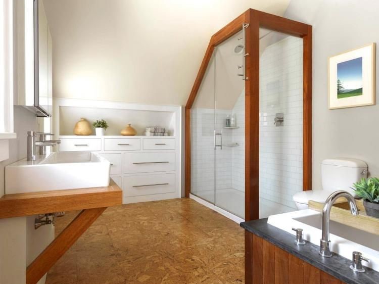 Lifestyle image of a white and brown bathroom design, featuring brown floor tiles, wooden countertop with a wide white double basin, wood panelled bath, white tiled shower enclosure with wooden pillars and integrated white cabinets with wooden handles