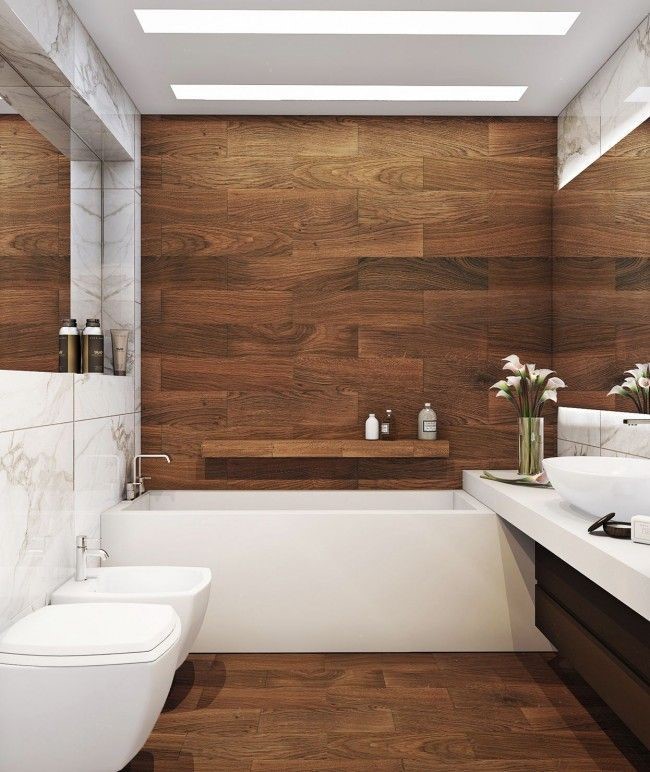 Lifestyle image of a brown and white bathroom design, featuring wooden floors and walls, a white marble tiled feature wall, white countertop and white ceramics
