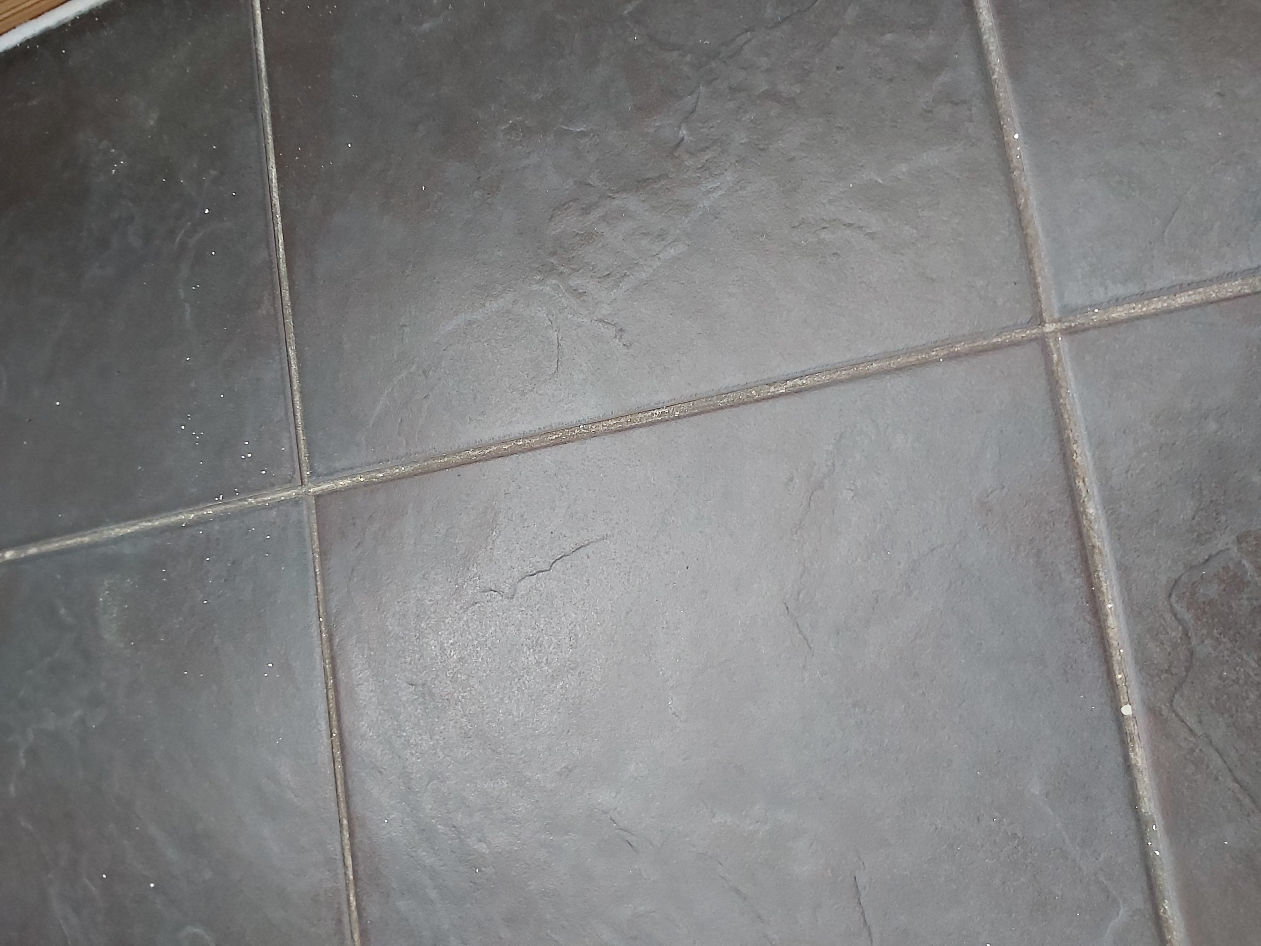 Close up image of grey floor tiles, spotted with white paint