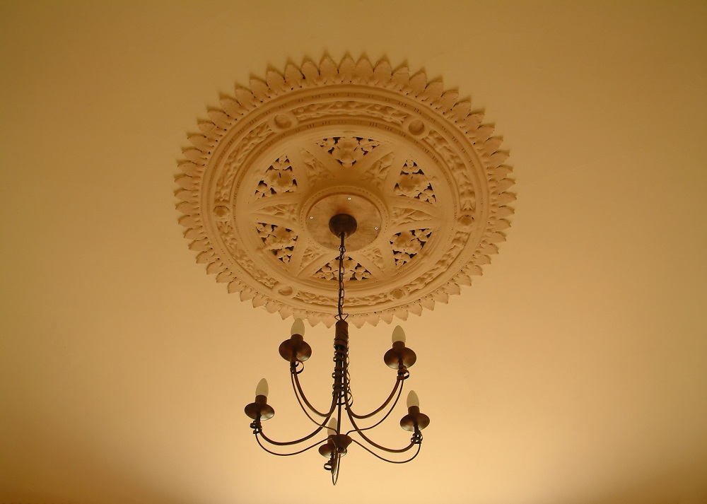 Lifestyle image of an ornate ceiling rose above a retrofitted chandelier