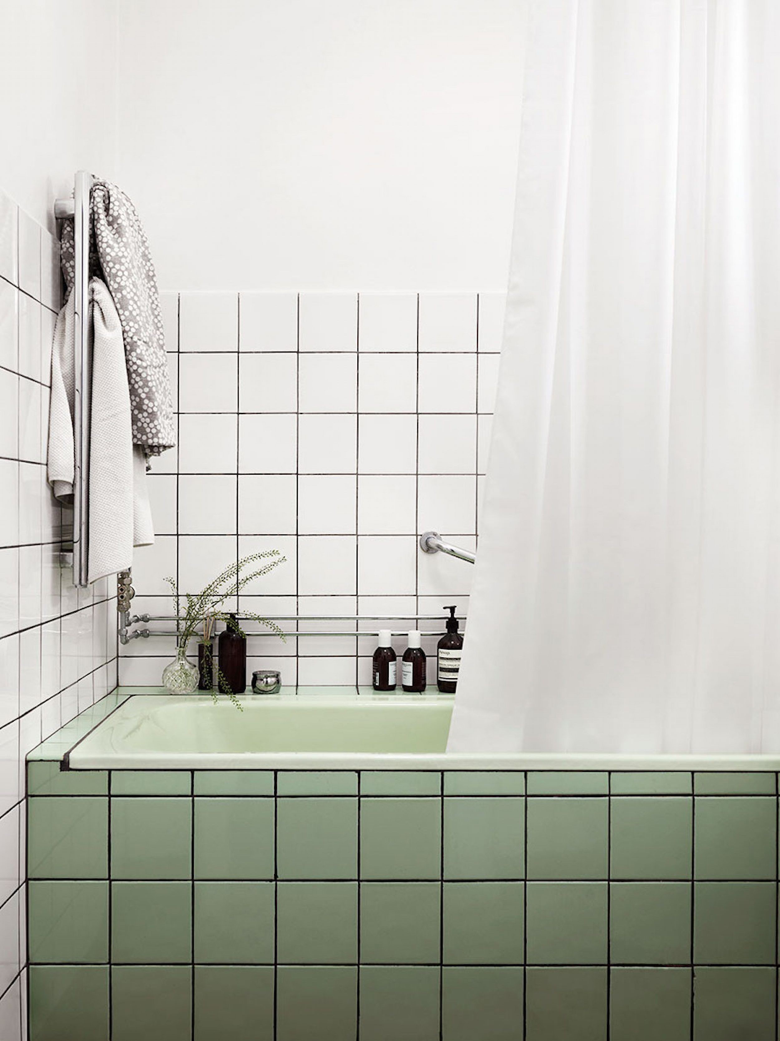 Close up lifestyle image of an avacado tiled bath contrast against white tiled walls