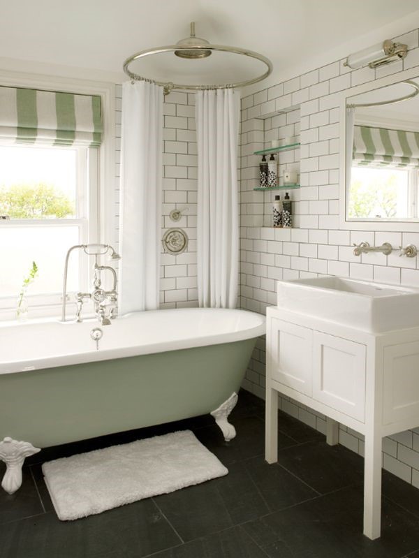Lifestyle image of a green and white bathroom design, featuring white tiled walls, green and white striped curtains and a pastel green roll top bath with white painted clawfeet
