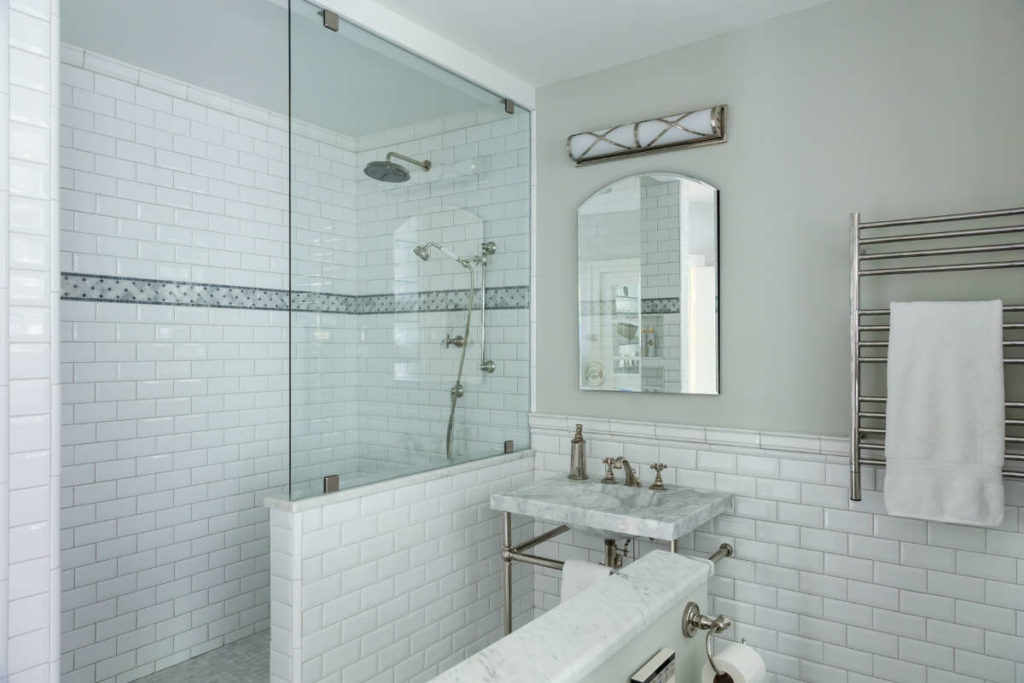 Lifestyle image of a grey and white bathroom design, with grey painted walls, white wall tiles, grey marble washbasin and a strip of grey tiles in the shower enclosure