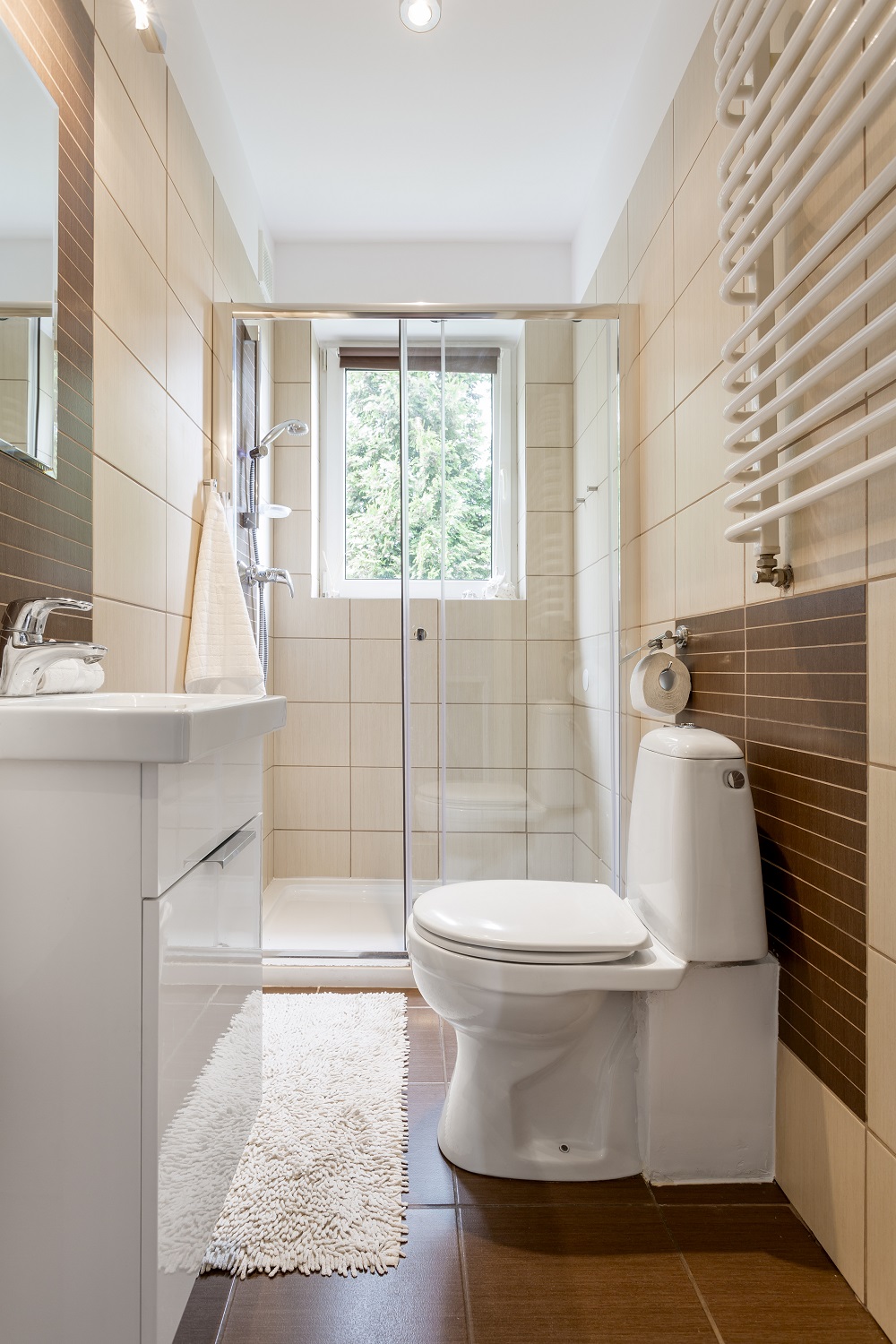 Lifestyle image of a small bathroom with small walk in shower, close coupled toilet and vanity unit with basin