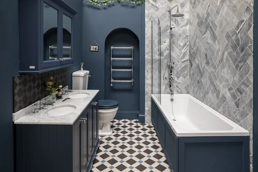 image of a blue bathroom with a double vanity unit and worktop basin with bayswater bathurst bath and panel fitted with shower screen, chrome shower system and grey marble parquet tiling on right