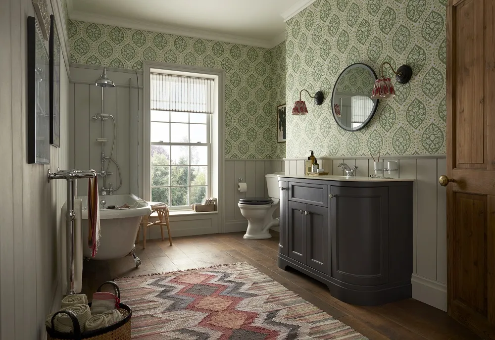 image of the heritage country house room shot featuring a wooden floor with rug, white and chrome traditional radiator, roll top freestanding shower bath, open back close coupled toilet & large vanity unit with worktop and chrome mono tap