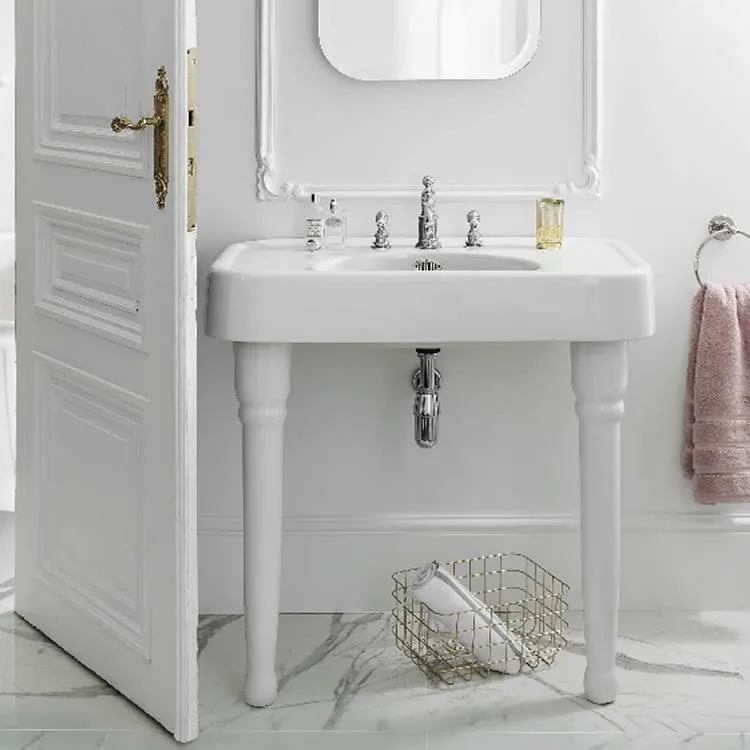 image of burlington arcade 900mm console basin with legs with 3 tap hole chrome taps and bottle trap in white coloured bathroom with marble floor