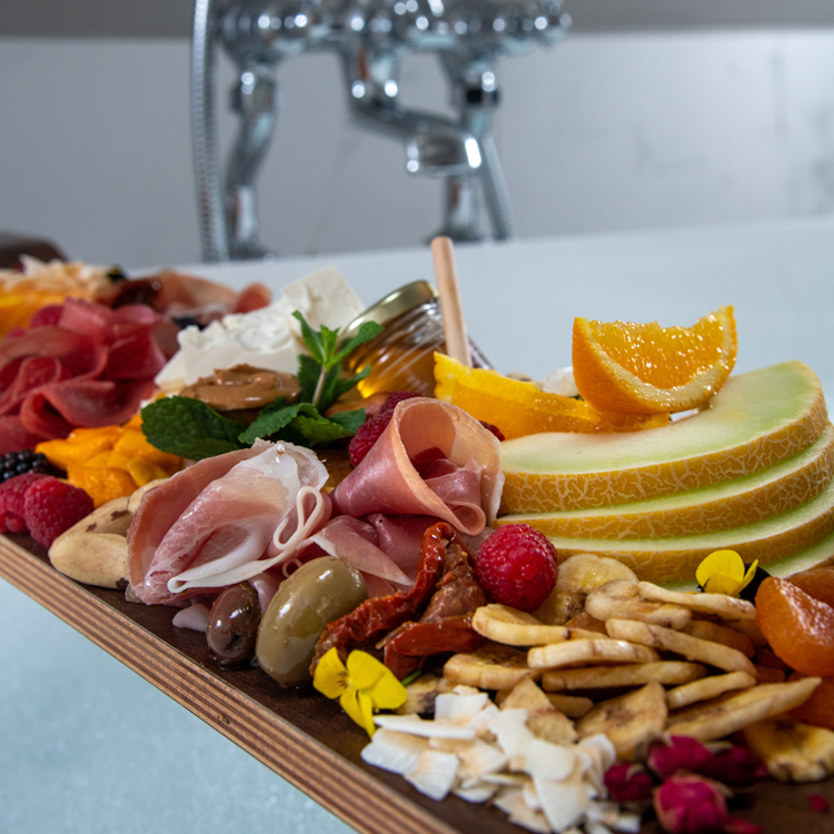 Close up image of a charcuterie board stretched across a bubble bath