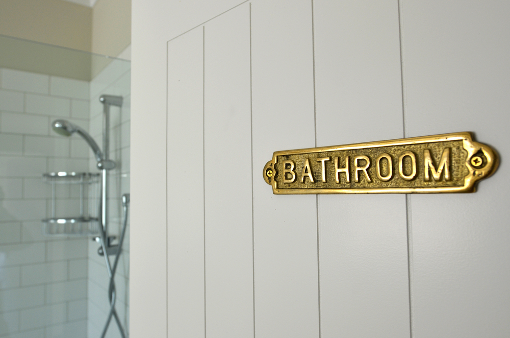 Close up image of an embossed 'BATHROOM' sign attached to a bathroom door