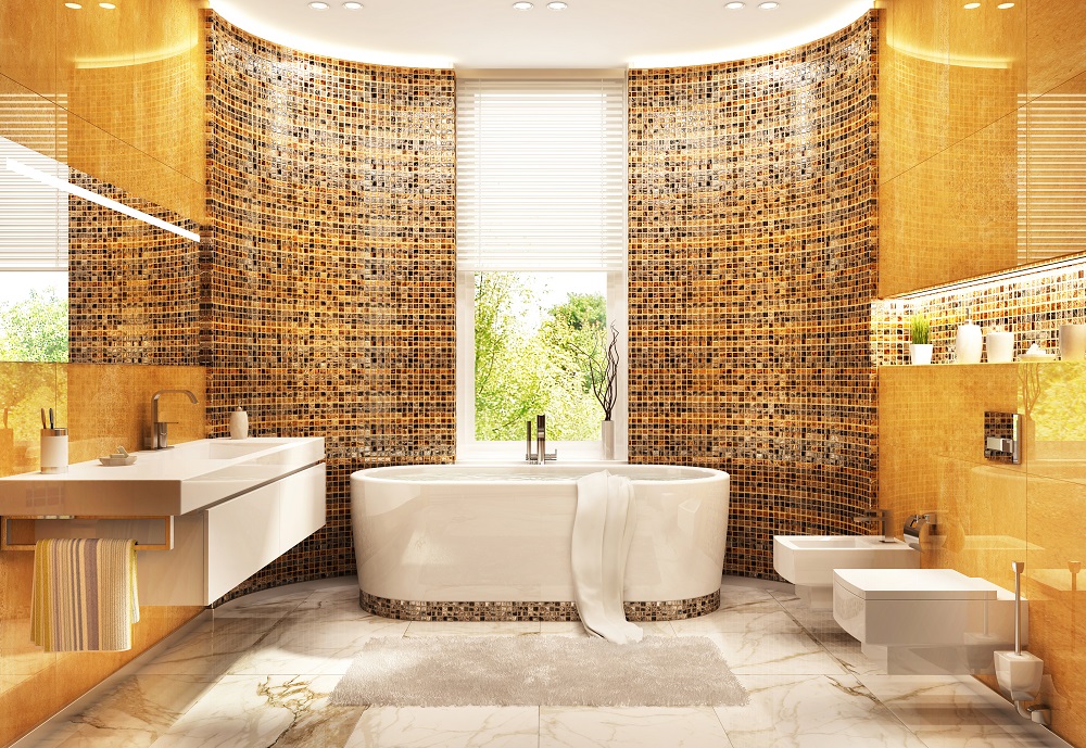 Lifestyle image of white and gold bathroom design, featuring large gold tiles, multiple shades of gold mosaic tiles, a freestanding bath and wall hung toilet and washbasin unit