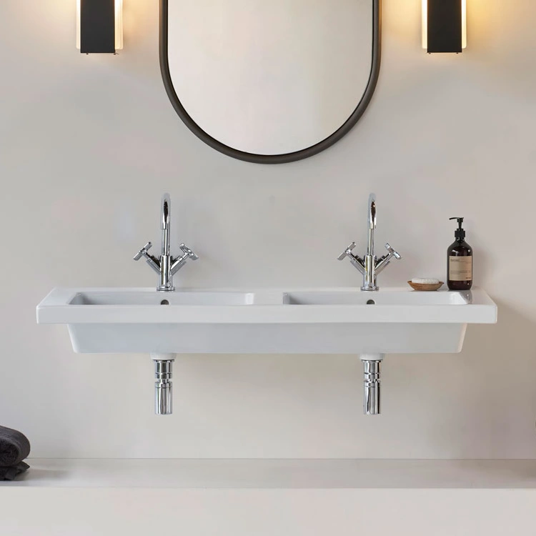 image of a double basin wall mounted on a white bathroom wall below a mirror
