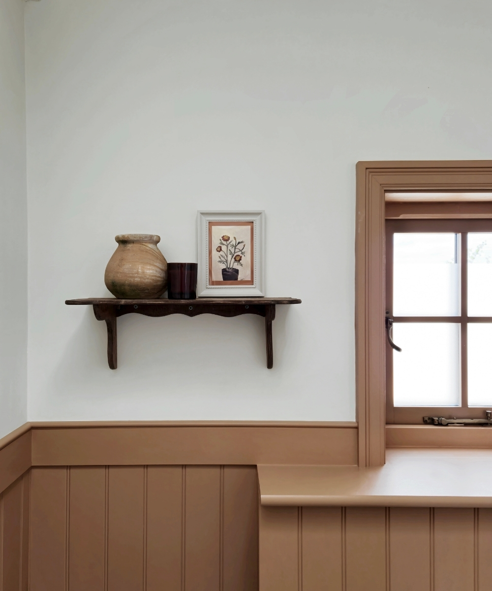 image of a bathroom shelf with decorative items in a brown wood panelled bathroom in a traditional style next to window