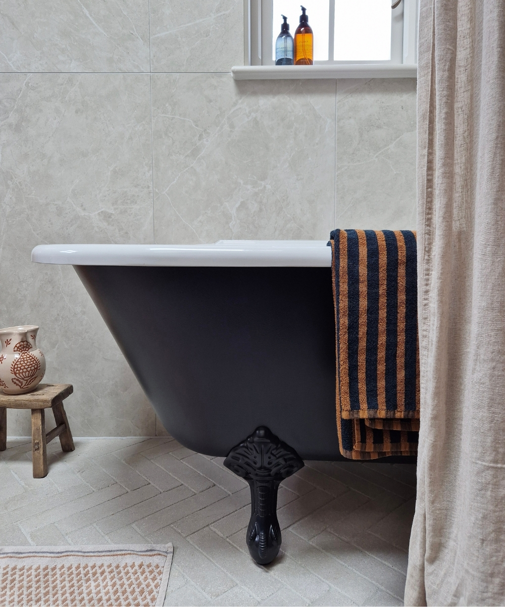 burlington hampton 1700 freestandind bath with black clawfoot feet in a grey tiled bathroom space with towel hanging over