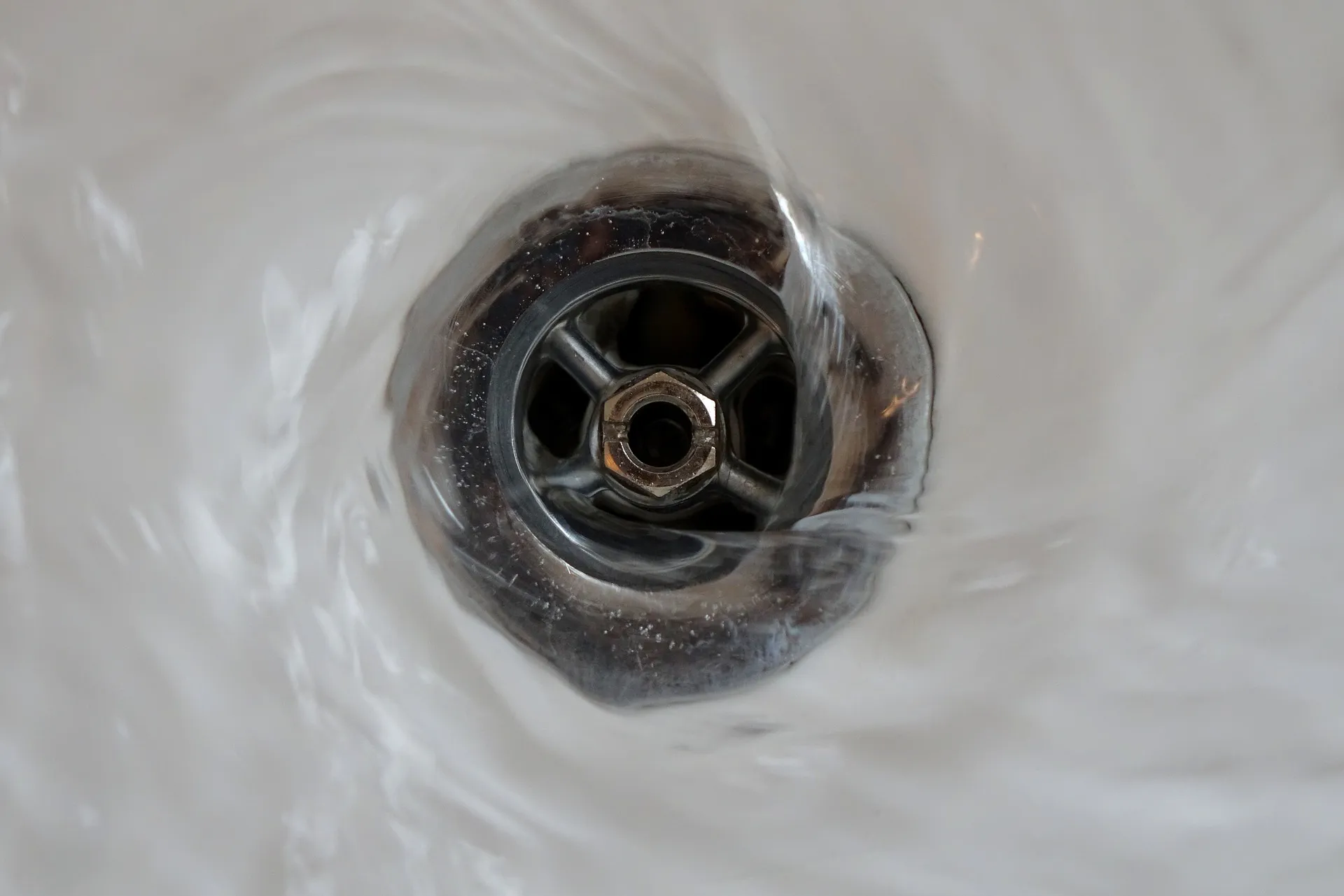 close up image of plug hole with water going down drain