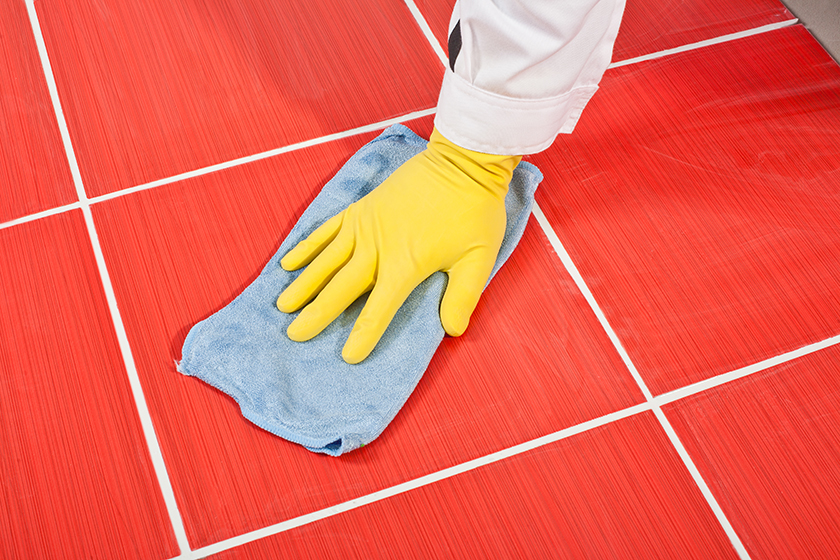 Close up image of someone wiping away excess grout with a damp cloth