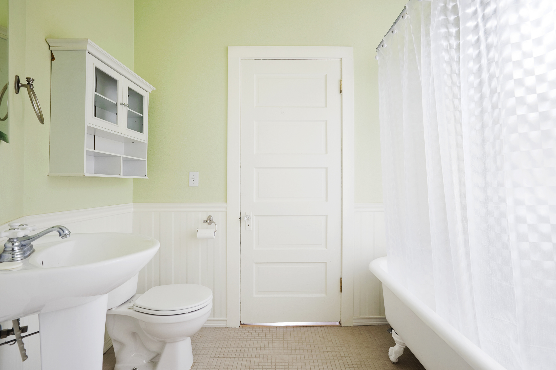 Lifestyle image of a bath with a shower curtain around it in a pastel green bathroom