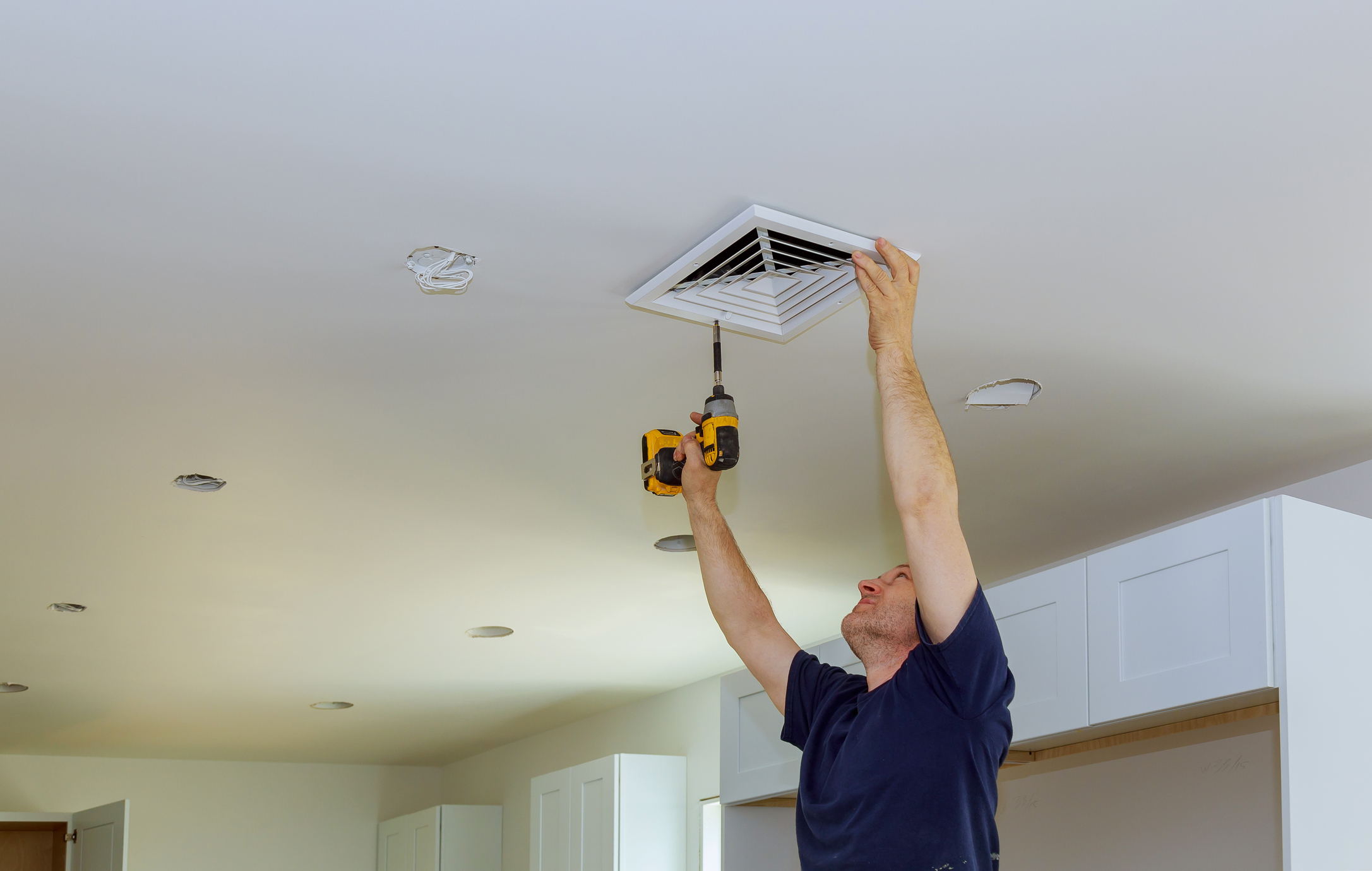 Lifestyle image of a man replacing the cover of his exhaust fan