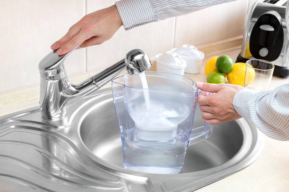 Lifestle image of a man filling a water filter jug from his kitchen sink