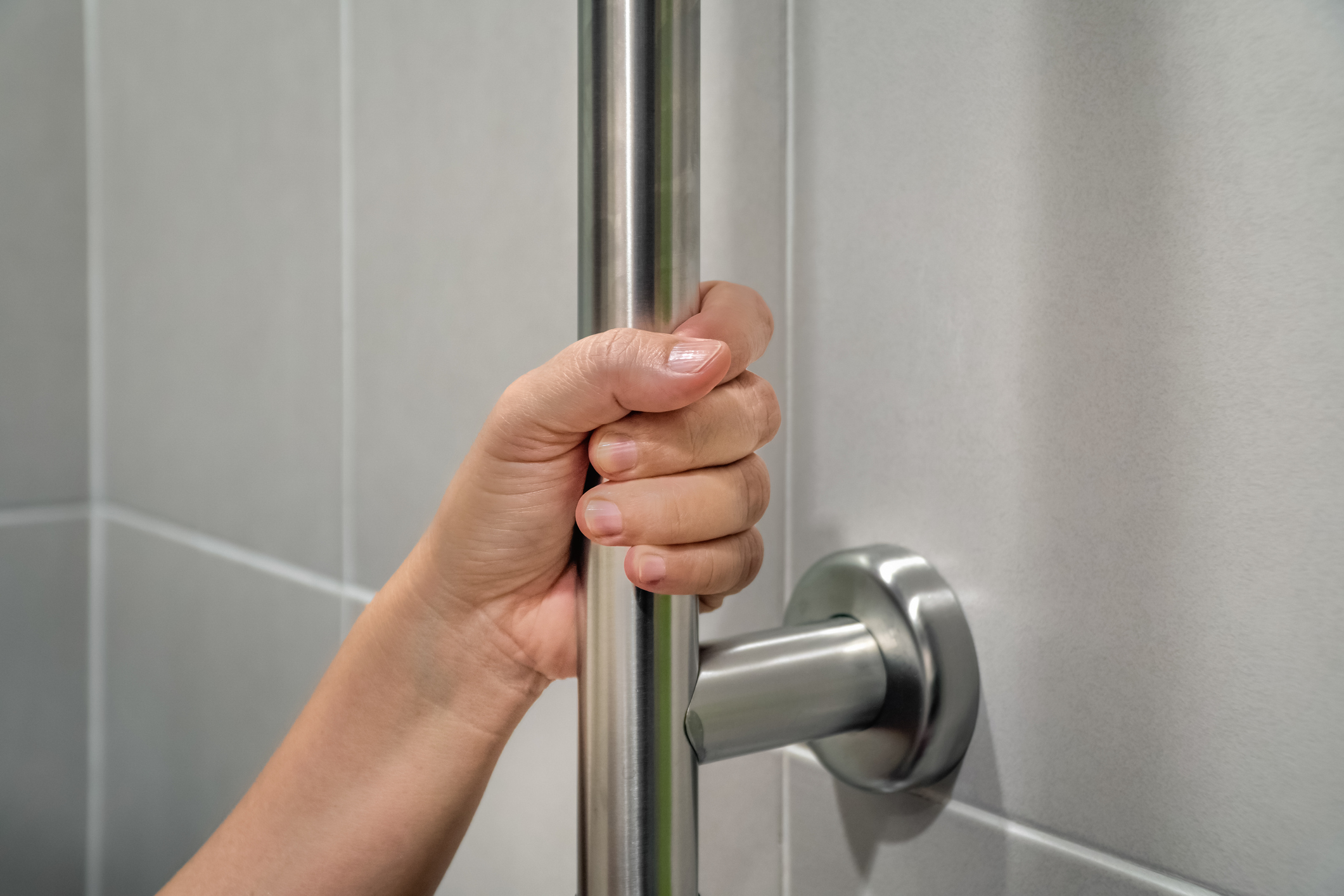 Close up image of someone holding onto a vertical grab bar to pull themselves up