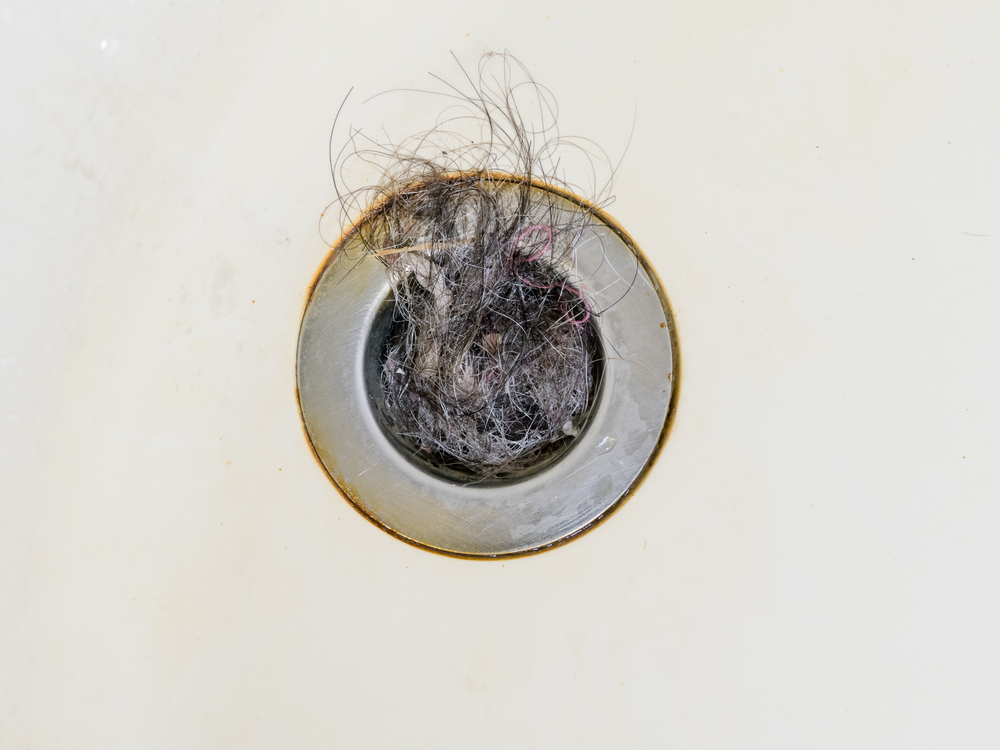 Close up image of hair clogging a bath plughole