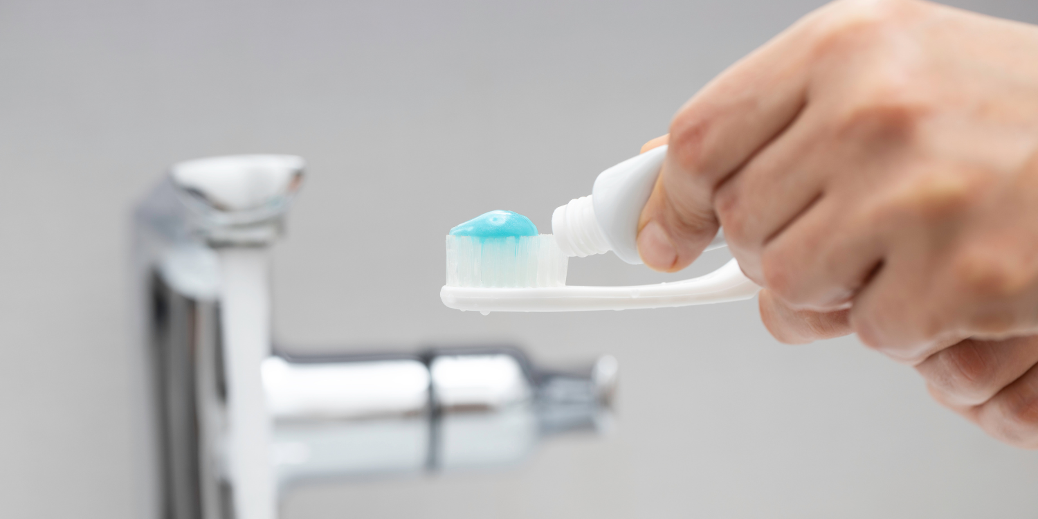 photo of toothpaste being applied to toothbrush in hand