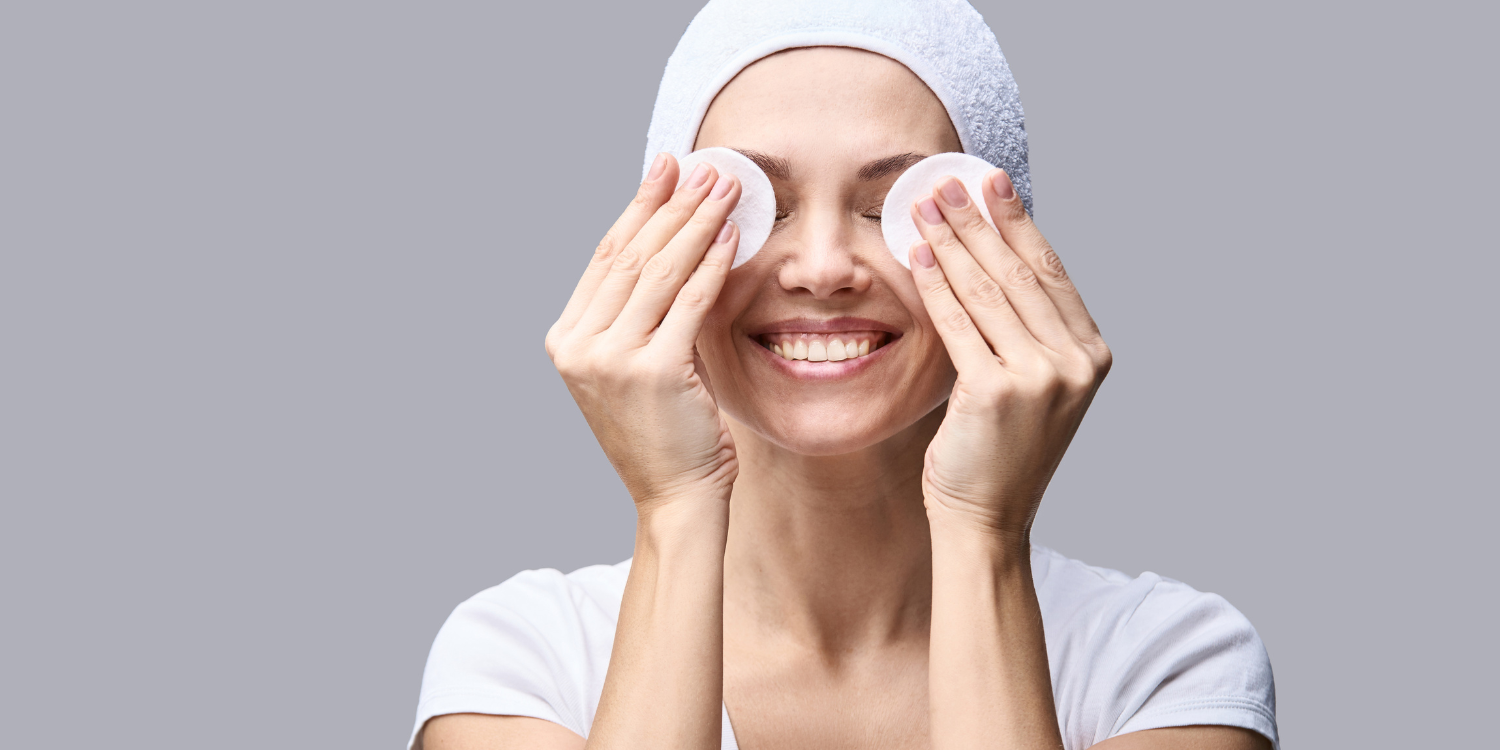 photo of woman with towel on head rubbing face with two cotton pads