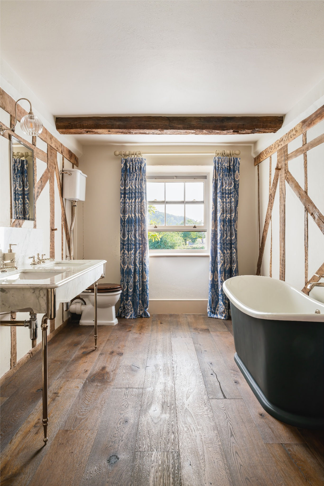 Traditional bathroom with exposed timber beams, a freestanding bath and marble basin