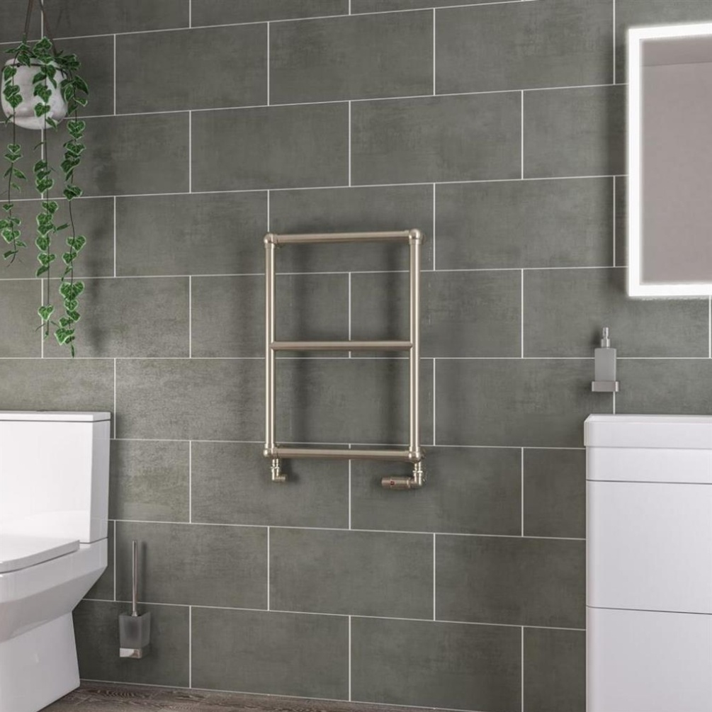 Lifestyle image of the Eastbrook Stour 690mm x 500mm Brushed Brass Heated Towel Rail mounted on a grey tiled bathroom wall