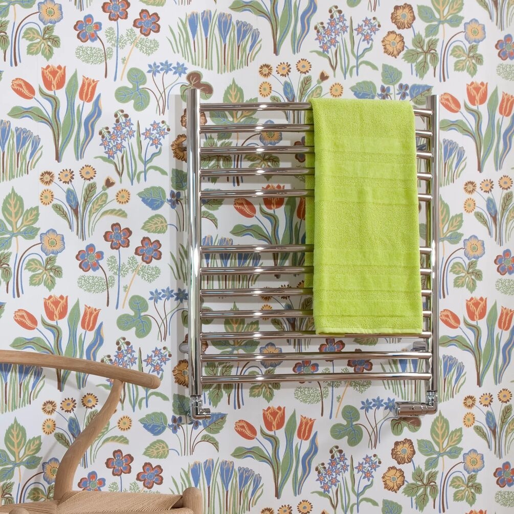 Lifestyle image of the The Sussex Range by JIS Camber 700mm x 620mm Polished Stainless Steel Curved Heated Towel Rail installed on a decorated wall with yellow towel