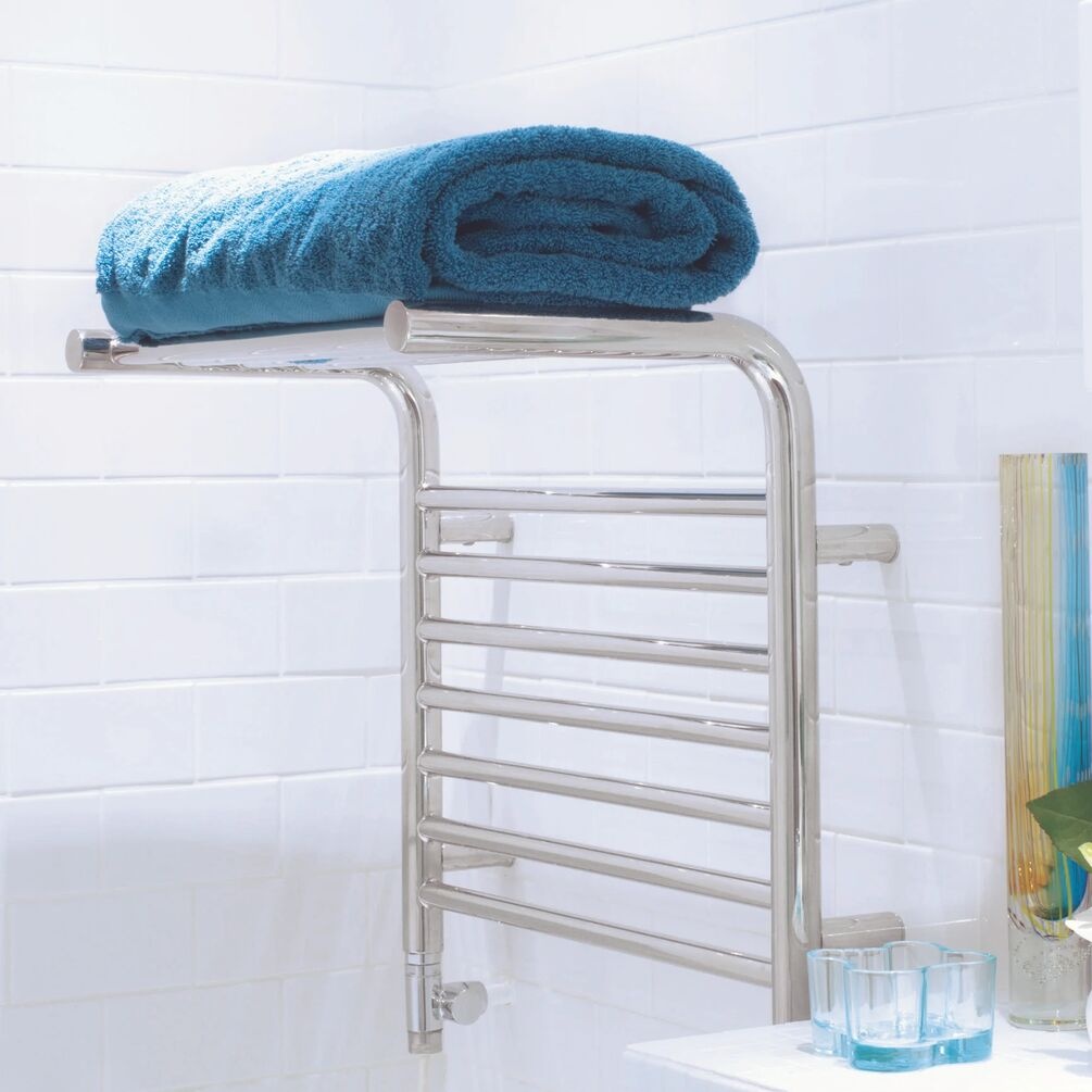 Lifestyle image of the The Sussex Range by JIS Newhaven 480mm x 520mm Polished Stainless Steel Heated Shelf Towel Rail installed at the bottom of a bath, with a towel on top