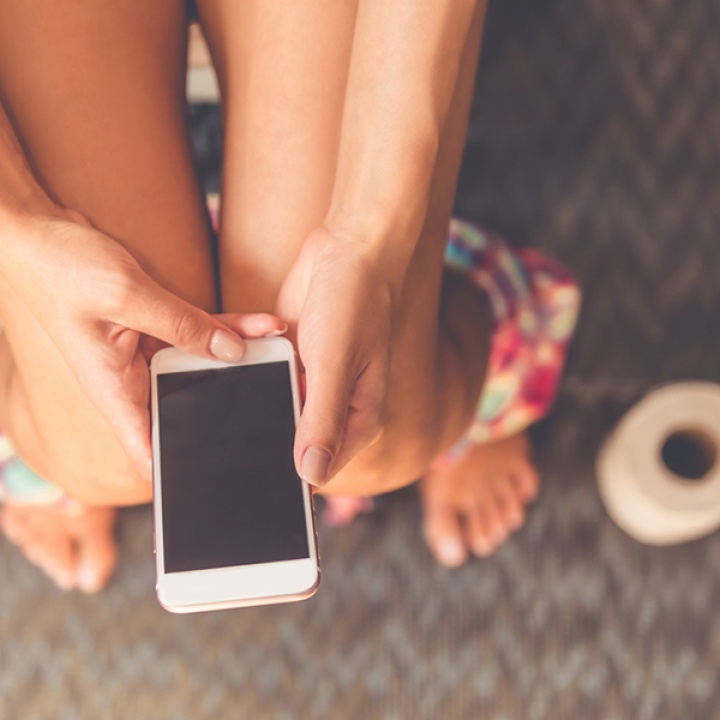 Close up image of someone using their phone while sitting on the toilet