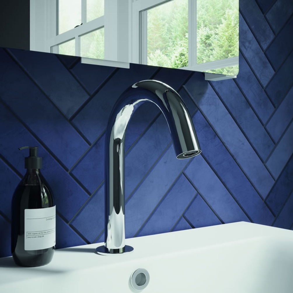 Lifestyle image of Crosswater MPRO Sensor Basin Deck Mounted Spout Chrome mounted on white basin against blue tiles.