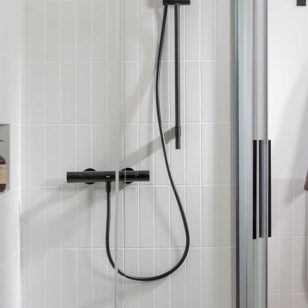 Lifestyle image of the Roca Flex Matt Black 1500mm Anti-Twist Shower Hose connected to a shower outlet and handheld shower head