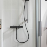 Lifestyle image of the Roca Flex Matt Black 1500mm Anti-Twist Shower Hose connected to a shower outlet and handheld shower head