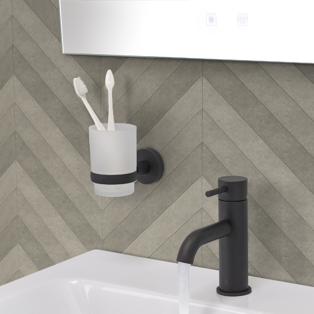 Close up product lifestyle image of the JTP Vos Matt Black Tumbler Holder mounted next to a mono basin mixer