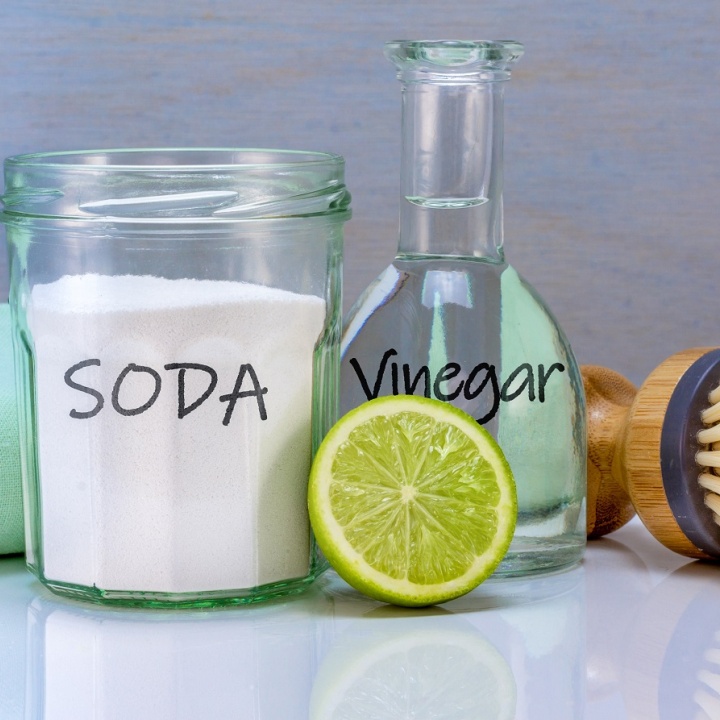 Close up image of various cleaning solutions, including bicarbonate of soda, white vinegar and a lime