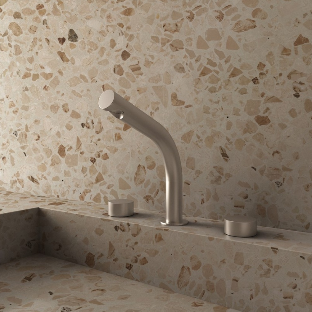 Lifestyle image of the Crosswater Ixora Stainless Steel 3 Tap Hole Deck Mounted Basin Mixer installed on a terrazzo style basin deck